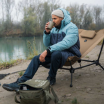 ein Mann trinkt ein Getränk im Campingstuhl